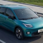Vehículo eléctrico compacto GAC AION UT en color verde turquesa circulando sobre el asfalto.