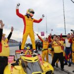Alex Palou celebra de pie sobre su monoplaza de Chip Ganassi Racing junto a su equipo tras ganar su quinto campeonato de IndyCar.