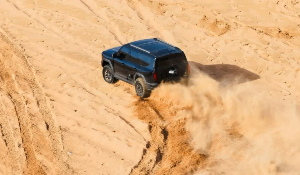 SUV todoterreno de color oscuro levantando arena mientras circula por las dunas del desierto del Sahara durante la expedición de Ed Stafford.