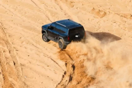 SUV todoterreno de color oscuro levantando arena mientras circula por las dunas del desierto del Sahara durante la expedición de Ed Stafford.