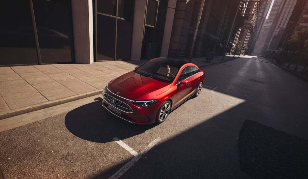 Vista superior del nuevo Mercedes-Benz CLA eléctrico color rojo estacionado en una calle urbana iluminada por el sol.