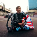 George Russell sentado en la pista junto a su trofeo y una bandera británica tras ganar el Gran Premio de Azerbaiyán de Fórmula 1 2026.