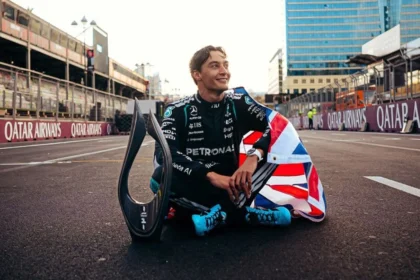 George Russell sentado en la pista junto a su trofeo y una bandera británica tras ganar el Gran Premio de Azerbaiyán de Fórmula 1 2026.