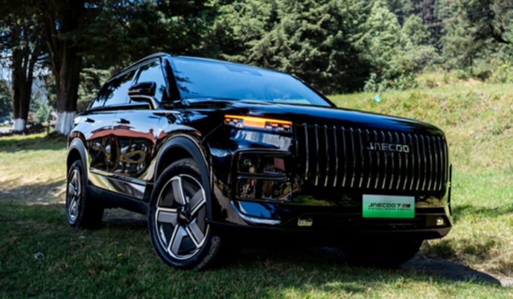 SUV híbrida enchufable JAECOO 7 SHS en color negro estacionada en una zona boscosa rodeada de árboles.
