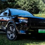 SUV híbrida enchufable JAECOO 7 SHS en color negro estacionada en una zona boscosa rodeada de árboles.
