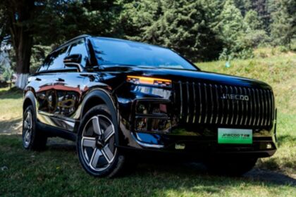 SUV híbrida enchufable JAECOO 7 SHS en color negro estacionada en una zona boscosa rodeada de árboles.