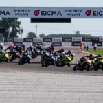 Grupo de motociclistas compitiendo en la pista bajo un arco publicitario del campeonato WorldSBK en el Circuito de Cremona.