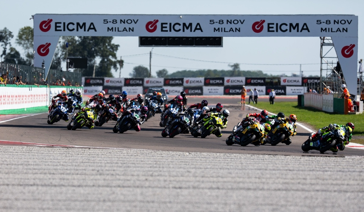 Grupo de motociclistas compitiendo en la pista bajo un arco publicitario del campeonato WorldSBK en el Circuito de Cremona.