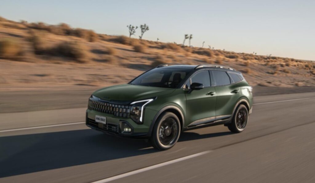SUV Kia Sportage 2027 color verde en movimiento sobre una carretera desértica.