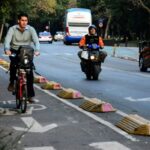 Ciclista y motociclista circulan junto a transporte público y automóviles en una vialidad de Ciudad de México.