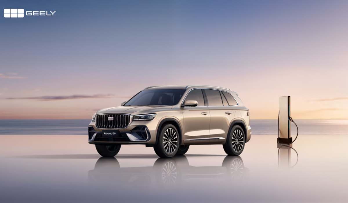 SUV Geely Monjaro EM-i híbrida enchufable color dorado estacionada junto a una estación de carga frente al mar.