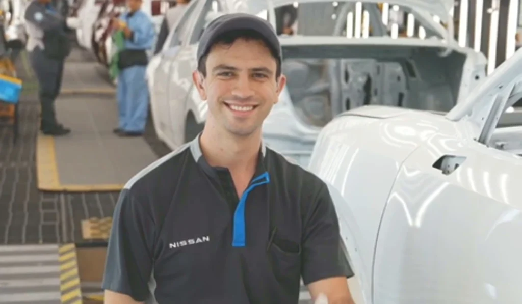 Luis Segoviano, inspector de calidad con discapacidad auditiva en la planta de Nissan Aguascalientes A1, sonriendo en la línea de producción.