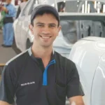 Luis Segoviano, inspector de calidad con discapacidad auditiva en la planta de Nissan Aguascalientes A1, sonriendo en la línea de producción.