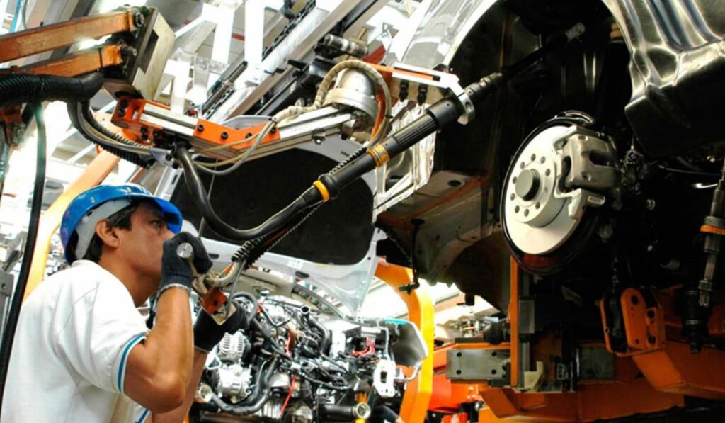 Operario de ensamblaje trabajando en la línea de producción automotriz de un vehículo en México.