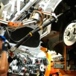Operario de ensamblaje trabajando en la línea de producción automotriz de un vehículo en México.