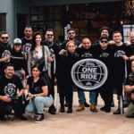 Grupo de motociclistas de la comunidad Royal Enfield posando juntos en camisetas negras con el logotipo oficial de One Ride.