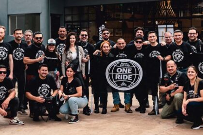 Grupo de motociclistas de la comunidad Royal Enfield posando juntos en camisetas negras con el logotipo oficial de One Ride.