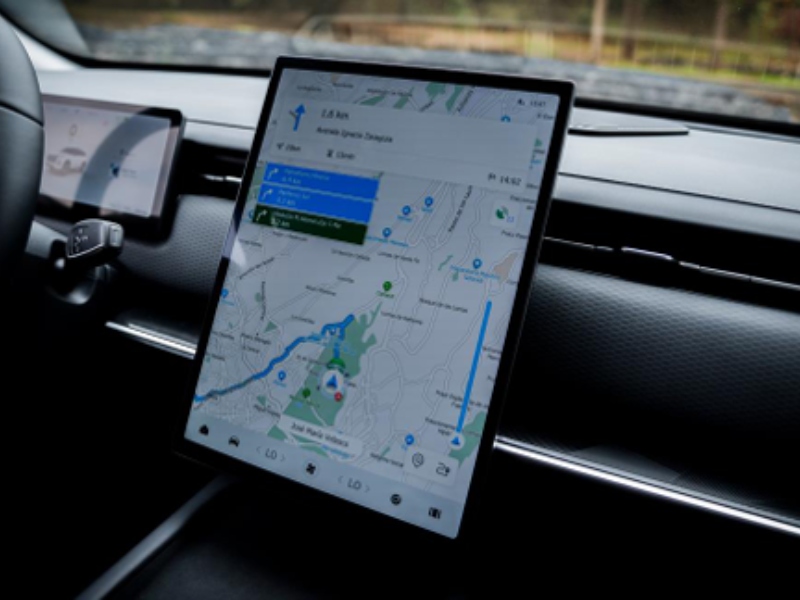 Pantalla táctil vertical de alta definición en el tablero de un vehículo mostrando un sistema de navegación GPS y rutas cartográficas.