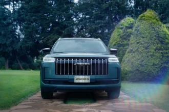 Vista frontal de la SUV JAECOO 5 de color verde estacionada en un camino pavimentado rodeado de áreas verdes y árboles.