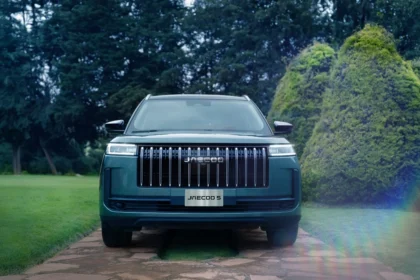 Vista frontal de la SUV JAECOO 5 de color verde estacionada en un camino pavimentado rodeado de áreas verdes y árboles.