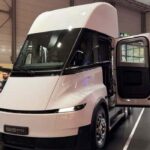 Vista frontal del camión eléctrico Tesla Semi color blanco con la puerta del conductor abierta en el centro de convenciones de IAA Transportation 2026.