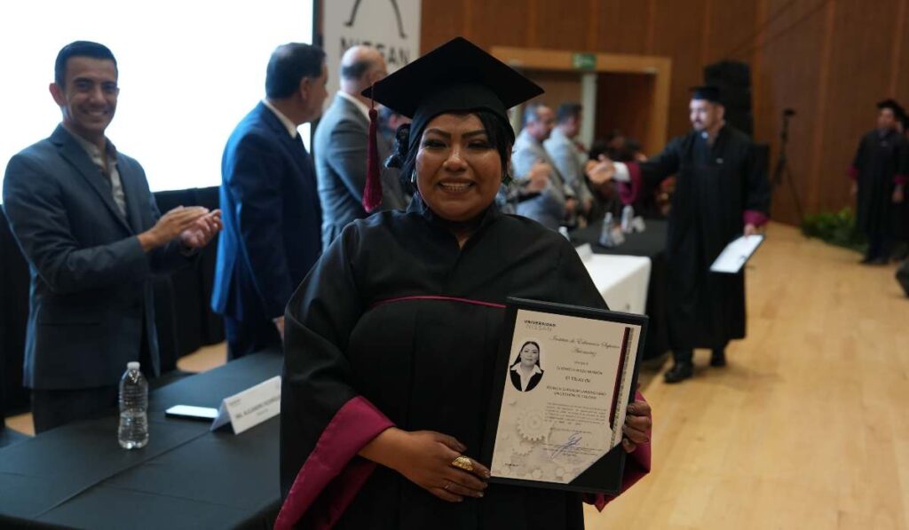 Egresada de la Universidad Nissan posando con birrete, toga y su título profesional durante la ceremonia de graduación.
