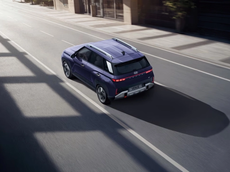 Vista superior trasera en movimiento de la nueva SUV subcompacta Hyundai VENUE en color morado sobre una calle urbana.