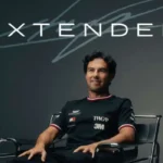 Sergio Checo Pérez sentado en una silla posando con playera de Cadillac F1 Team frente al gráfico oficial de anuncio de contrato extendido.