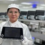 Colaboradora de FORVIA Clarion Electronics mostrando una pantalla de entretenimiento e infoentretenimiento automotriz en la planta de San Juan del Río, Querétaro.