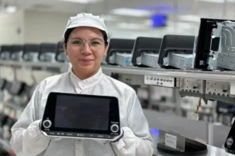 Colaboradora de FORVIA Clarion Electronics mostrando una pantalla de entretenimiento e infoentretenimiento automotriz en la planta de San Juan del Río, Querétaro.