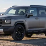 SUV GWM H7 en color gris mate con diseño boxy, tracción integral AWD y rines de aluminio negros de 19 pulgadas sobre camino de tierra.