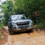 Camioneta pickup JETOUR F700 superando un obstáculo de lodo en un camino de montaña durante una prueba todoterreno en Moganshan, China.
