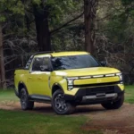 Pickup Nissan Frontier PRO PHEV color amarillo verdoso estacionada en un camino boscoso mostrando su diseño frontal Ruggedtech.