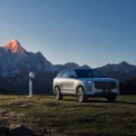 SUV JAECOO 7 estacionado en un paisaje montañoso junto a un punto de carga para vehículos de nuevas energías.