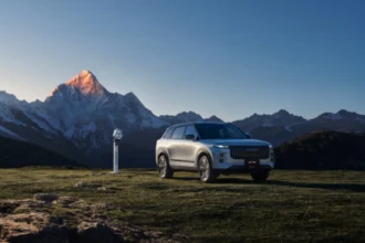 SUV JAECOO 7 estacionado en un paisaje montañoso junto a un punto de carga para vehículos de nuevas energías.