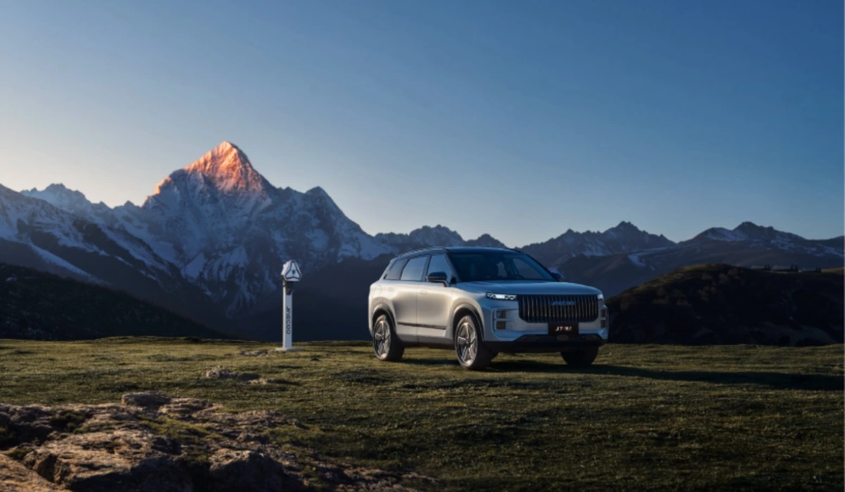 SUV JAECOO 7 estacionado en un paisaje montañoso junto a un punto de carga para vehículos de nuevas energías.