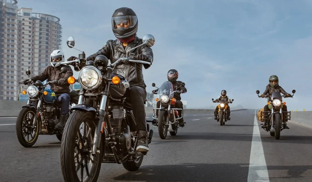 Grupo de motociclistas conduciendo motocicletas Royal Enfield con equipo de protección completo en una carretera.
