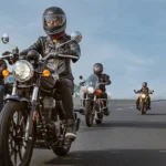 Grupo de motociclistas conduciendo motocicletas Royal Enfield con equipo de protección completo en una carretera.