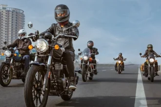 Grupo de motociclistas conduciendo motocicletas Royal Enfield con equipo de protección completo en una carretera.